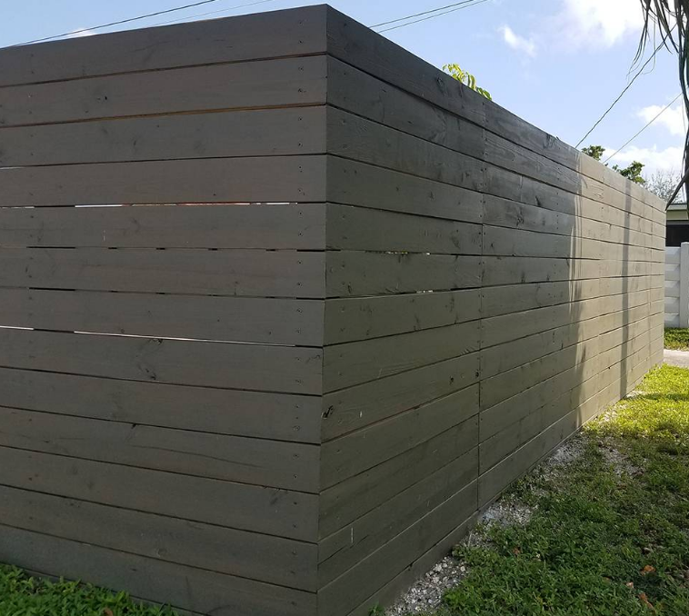 A wooden fence is sitting in the grass next to a house