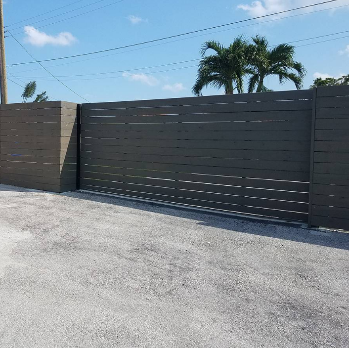 A black fence with palm trees in the background