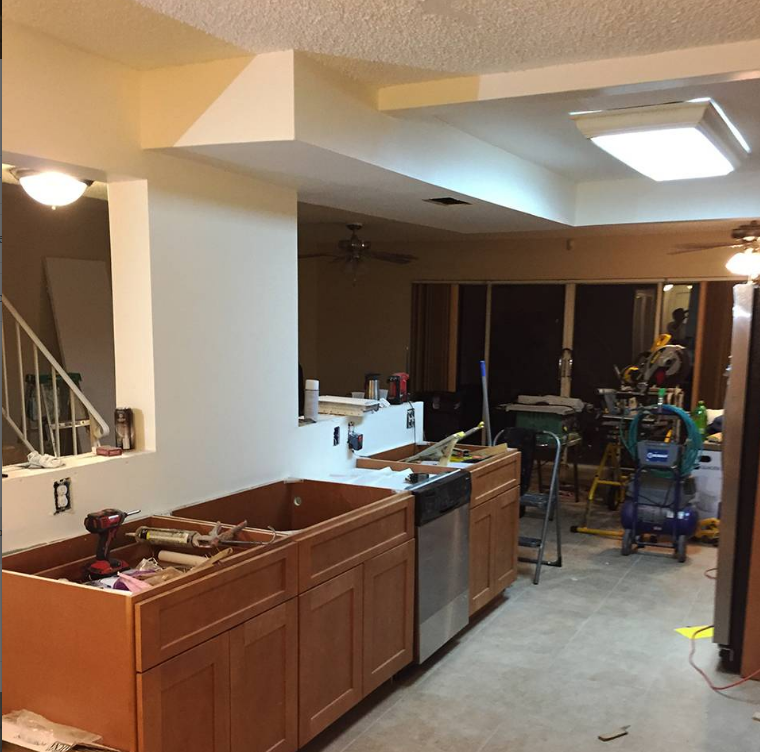 A kitchen under construction with wooden cabinets and stainless steel appliances