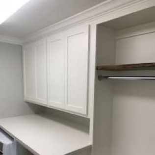 White laundry room with cabinets, counter, and closet.