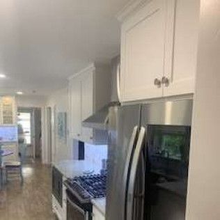 Kitchen interior with white cabinets, stainless steel refrigerator and dark countertops.