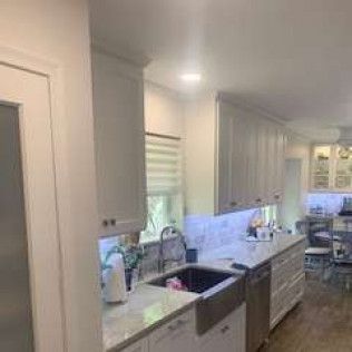 Kitchen interior with white cabinets, stainless steel sink, and light-colored countertops.