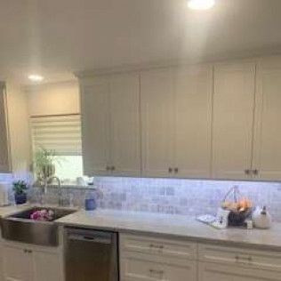 Kitchen with white cabinets, light countertop, and under-cabinet lighting.
