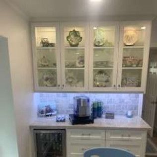Built-in cabinets with glass doors, a countertop, and mini-fridge in a kitchen.