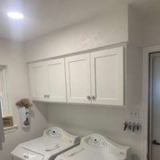 White laundry room with overhead cabinets and appliances.