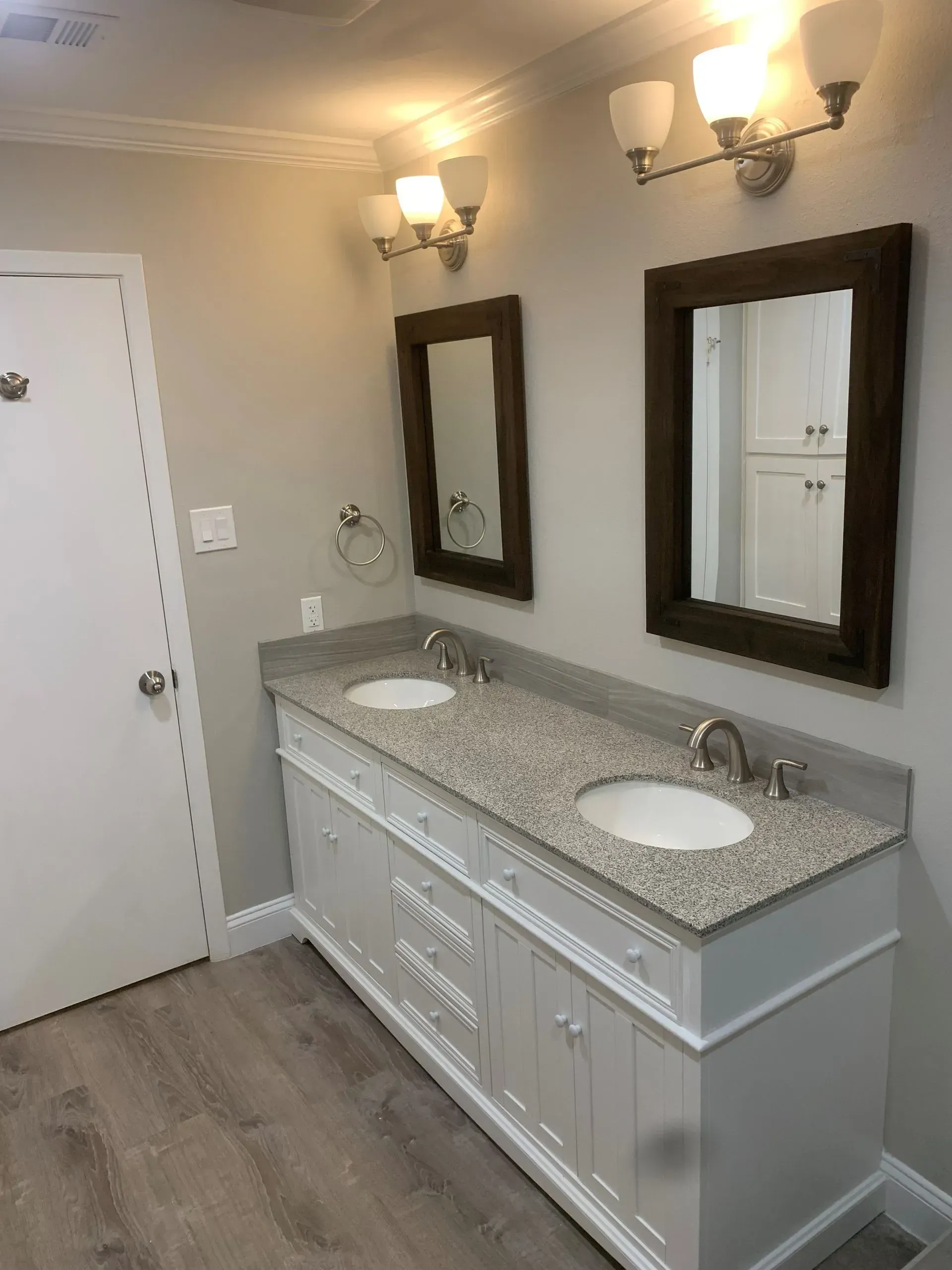 Bathroom with a double vanity. White cabinet, granite countertop, two mirrors, and overhead lighting.