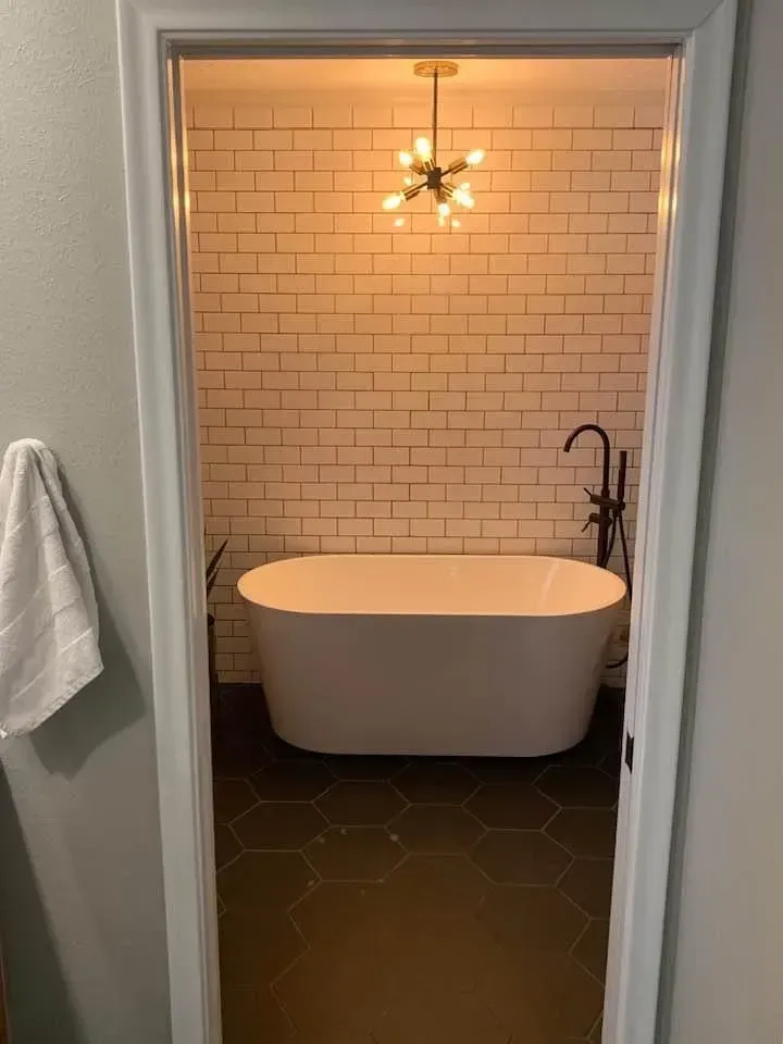 Bathroom interior with a white bathtub, subway tile, and a decorative light fixture.