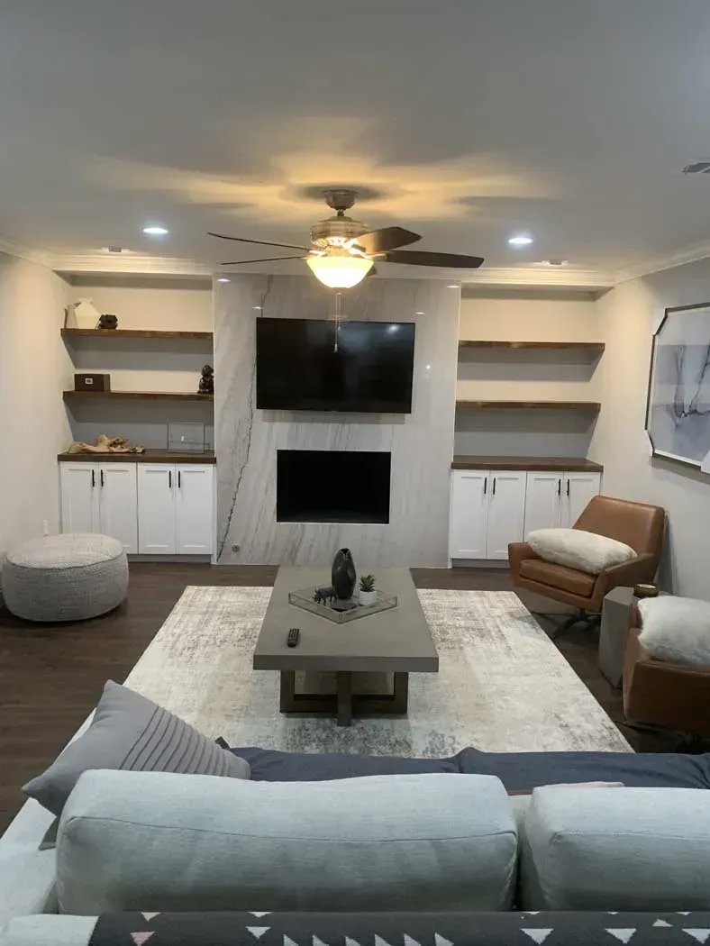 Modern living room with built-ins, shelves, and fireplace, centered on a rug.
