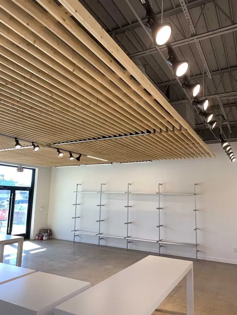 Interior of a store with a wooden slat ceiling, white walls, and display shelving.