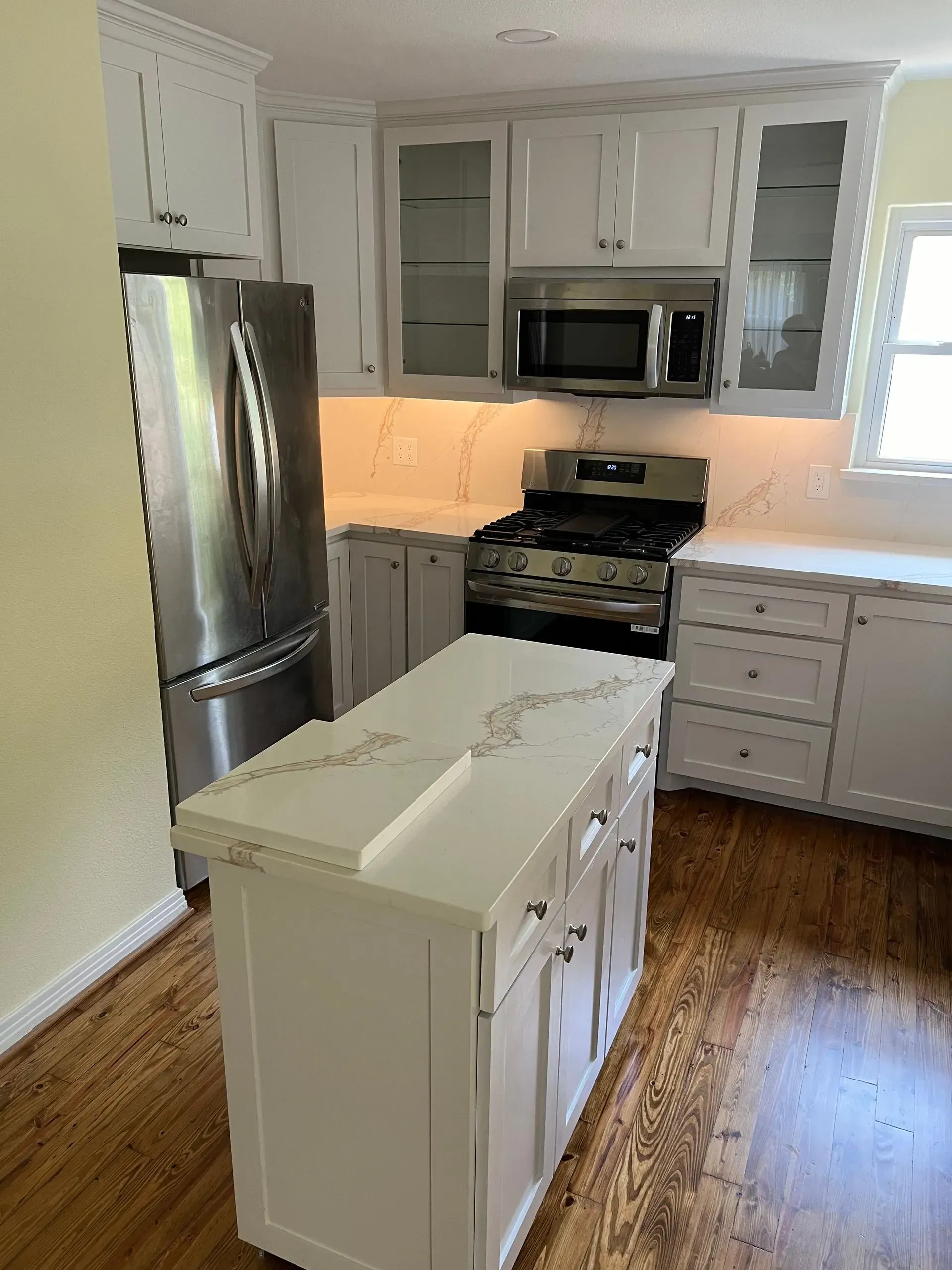 White kitchen with island, stainless steel appliances, and white countertops.