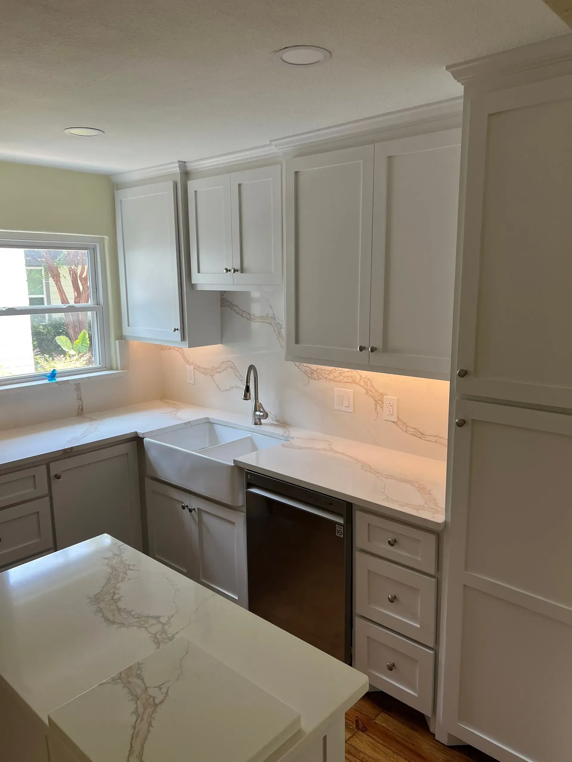 White kitchen with cabinets, countertops, stainless steel appliances, and a farmhouse sink.