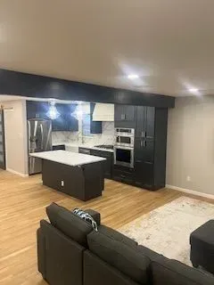 Modern kitchen with dark cabinetry, white countertops, and island. 