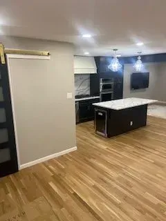 Modern kitchen with dark cabinetry, white countertops, and hardwood floors.