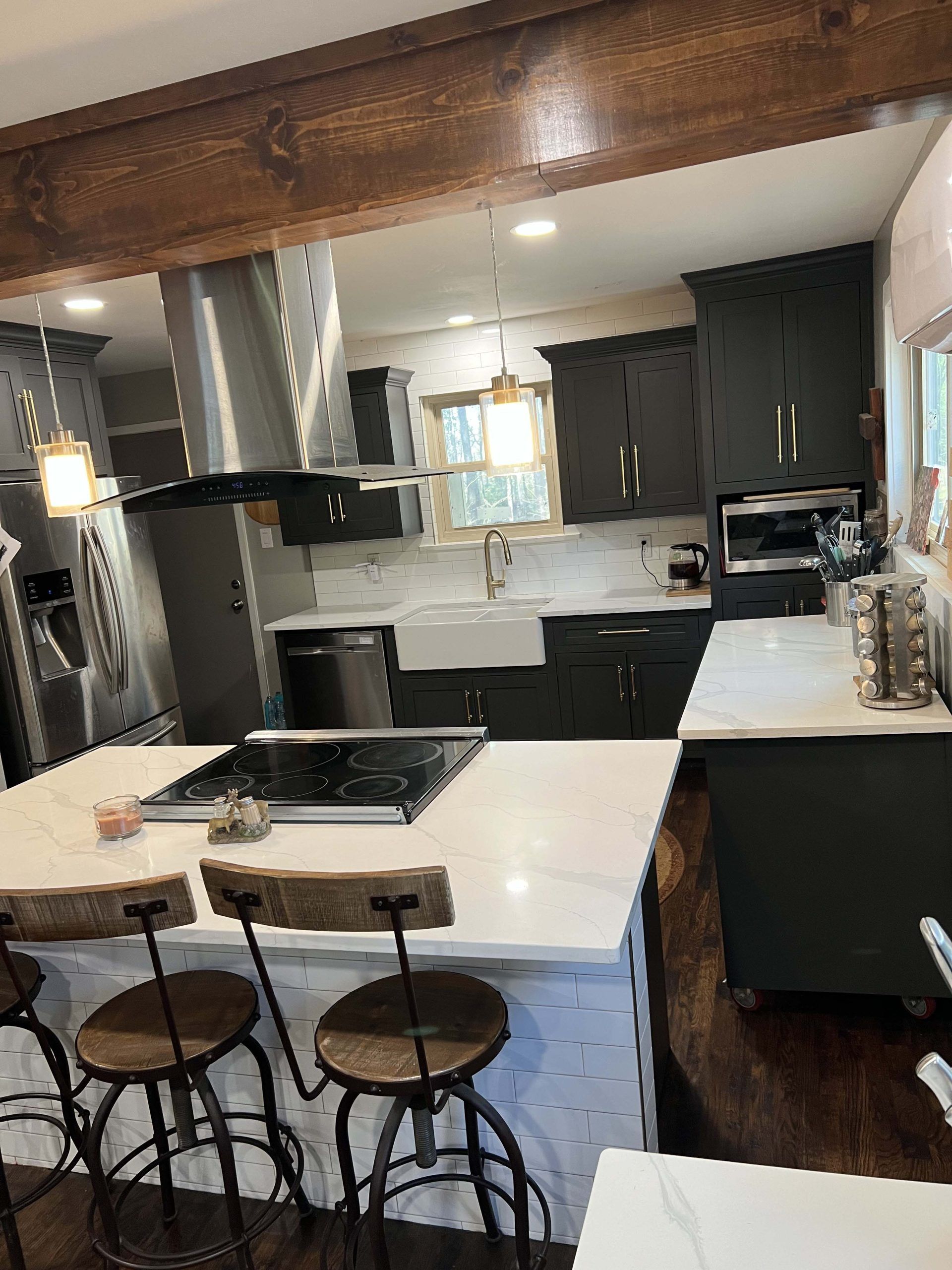 Modern kitchen with dark green cabinets, white countertops, and wooden accents.