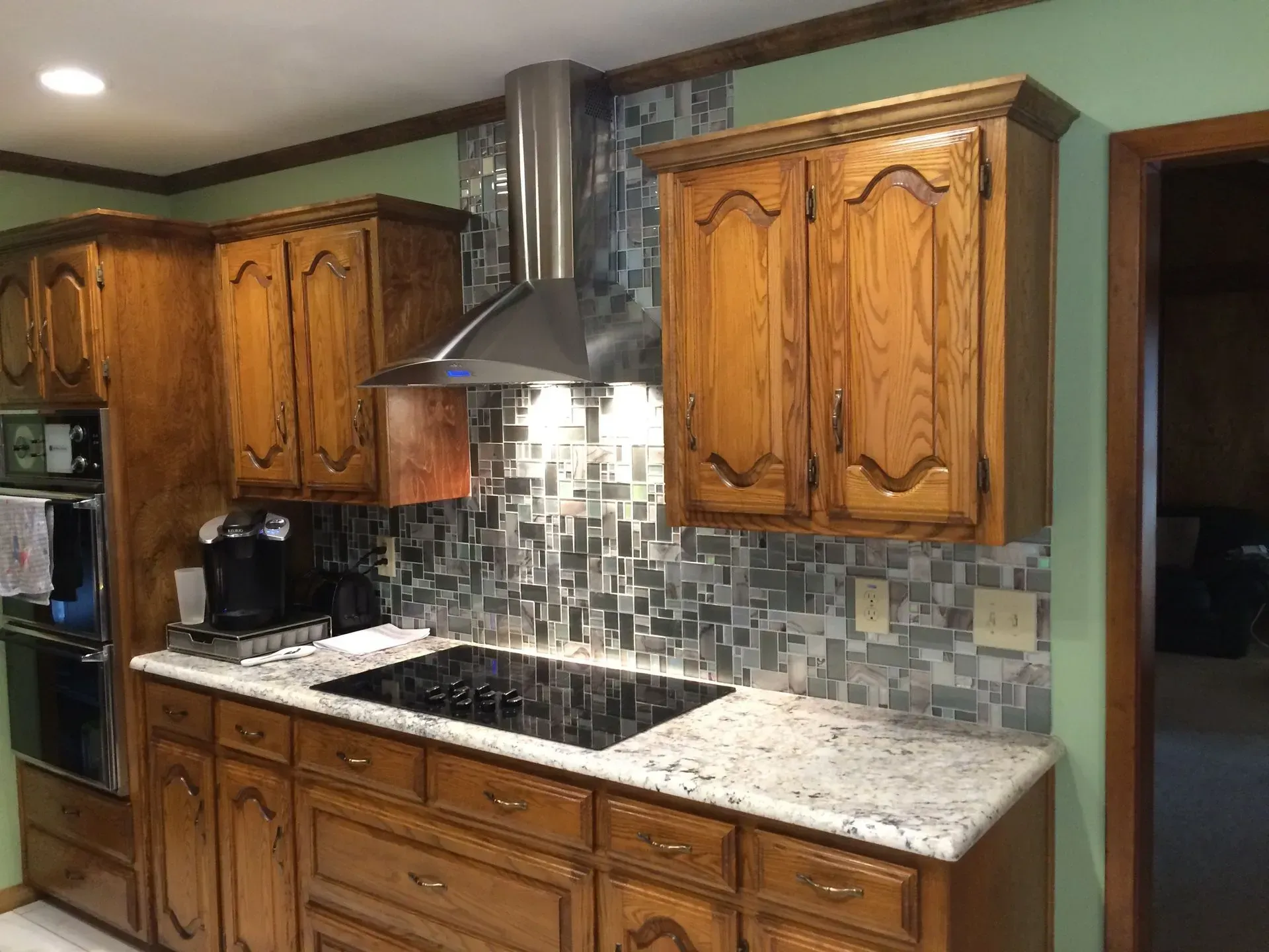 Kitchen with wooden cabinets, a stainless steel range hood, and a decorative tile backsplash.