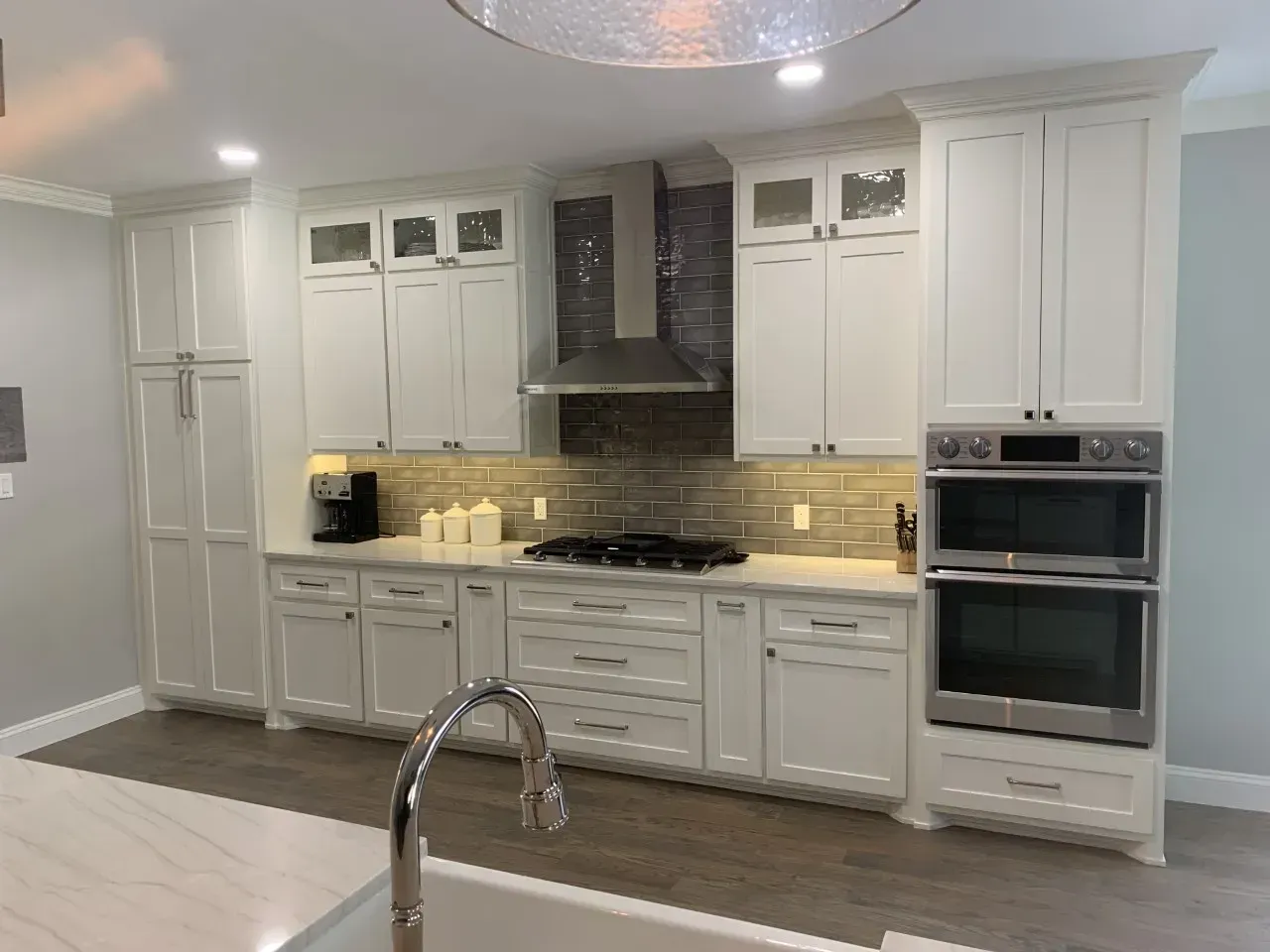White kitchen cabinets with stainless steel appliances and backsplash.