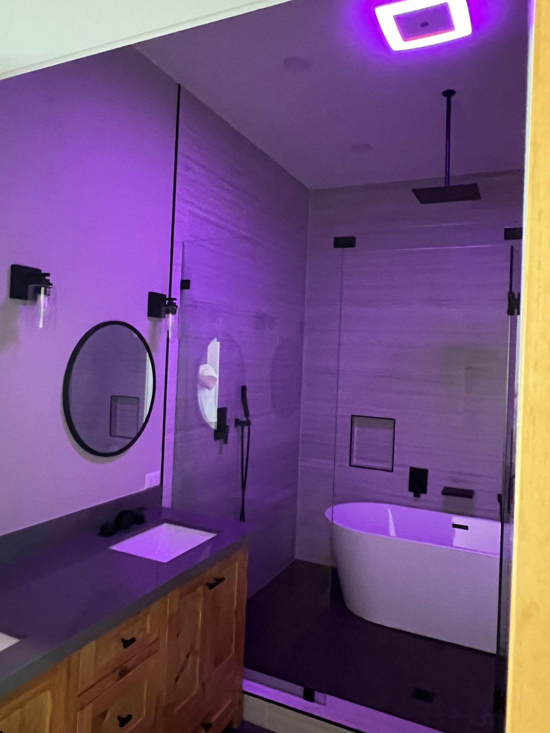 Modern bathroom with shower, tub, and vanity lit with purple light.