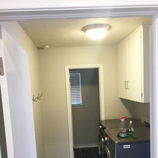 Laundry room with washer, dryer, cabinets, and a doorway with blinds.