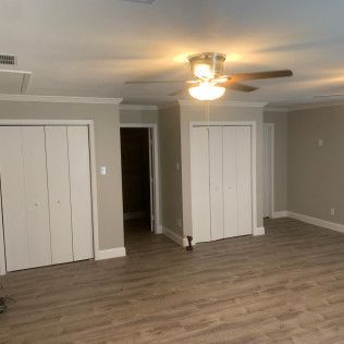 A room with wood-look flooring, two white closets, and a ceiling fan.