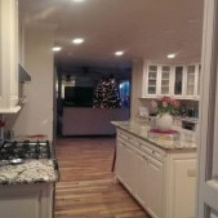 Kitchen with island and cabinets, view into hallway with Christmas tree.