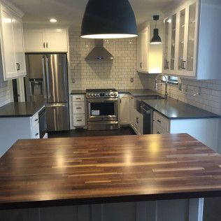 Modern kitchen with white cabinets, stainless steel appliances, and a wooden island.