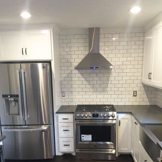 Kitchen with stainless steel appliances, white cabinets, and subway tile backsplash.