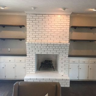 White brick fireplace with built-in shelves and cabinets; a chair in front.