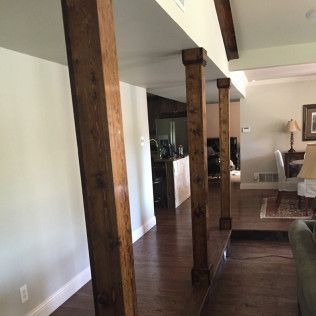 Wooden support beams in a hallway, with hardwood floors and white walls.