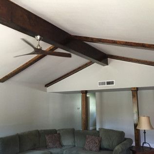Living room with wood beams, a ceiling fan, and a green sectional sofa.