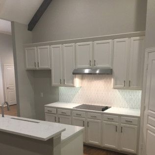 White kitchen cabinets with stainless steel range hood and white countertop.