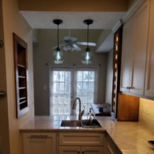 Kitchen with overhead lighting, cabinets, countertop, and window to the outside.