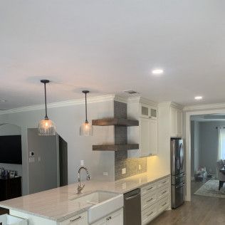 Modern kitchen with white cabinets, island, and stainless steel appliances.