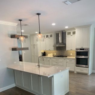 White kitchen with island, cabinets, range, and two pendant lights.