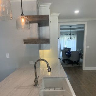 Kitchen with sink and faucet, floating shelves, and dining room in the background.