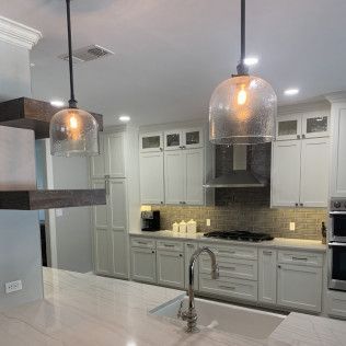 Kitchen with white cabinets, pendant lights, and stainless steel appliances.