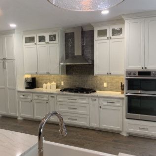 White kitchen with cabinets, stainless steel appliances, and a mosaic tile backsplash.