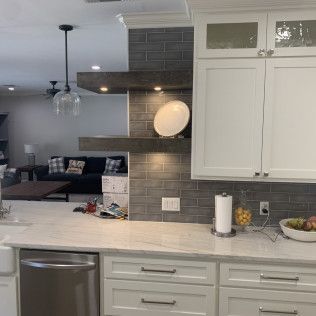 Kitchen with white cabinets, marble countertop, stainless steel appliances, and gray tile backsplash.