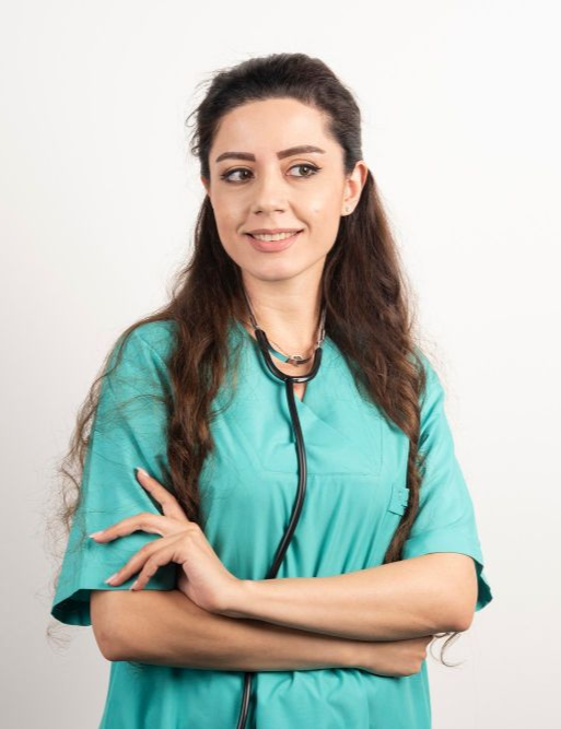 Mulher vestindo uniforme cirúrgico verde-azulado e estetoscópio, braços cruzados, sorrindo.
