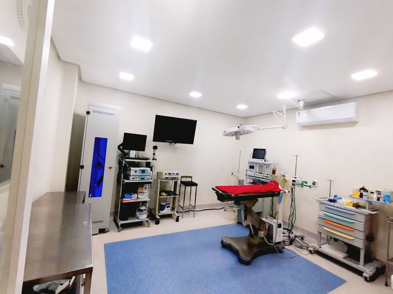 Interior de uma clínica. Pessoas de uniforme cirúrgico trabalham perto de equipamentos e expositores. 