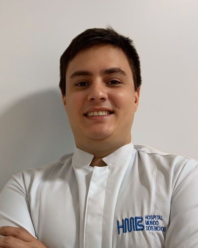 Mulher vestindo uniforme cirúrgico verde-azulado e estetoscópio, braços cruzados, sorrindo.