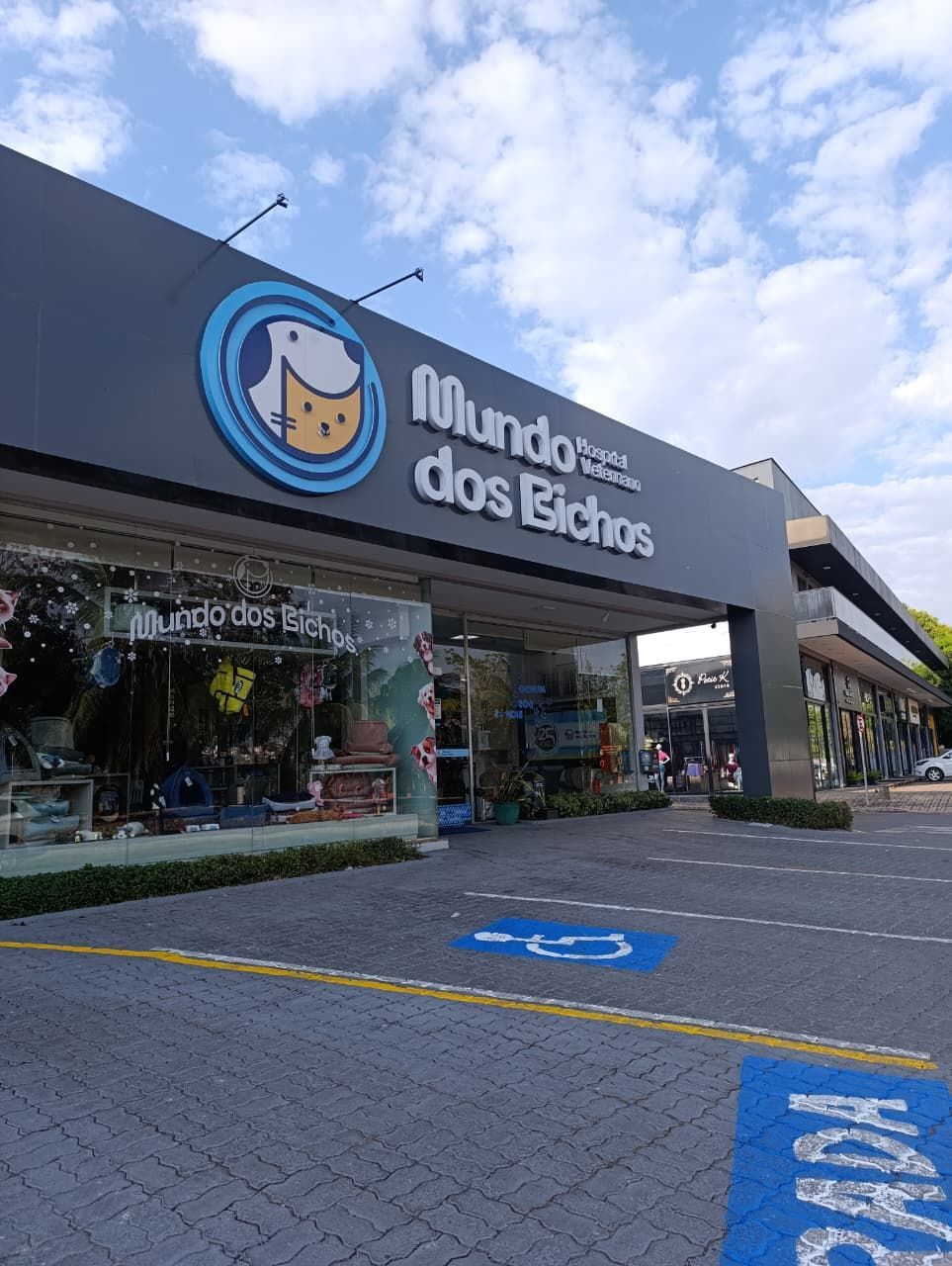 Veterinária de uniforme azul com um gato e um cachorro em uma sala de exames.
