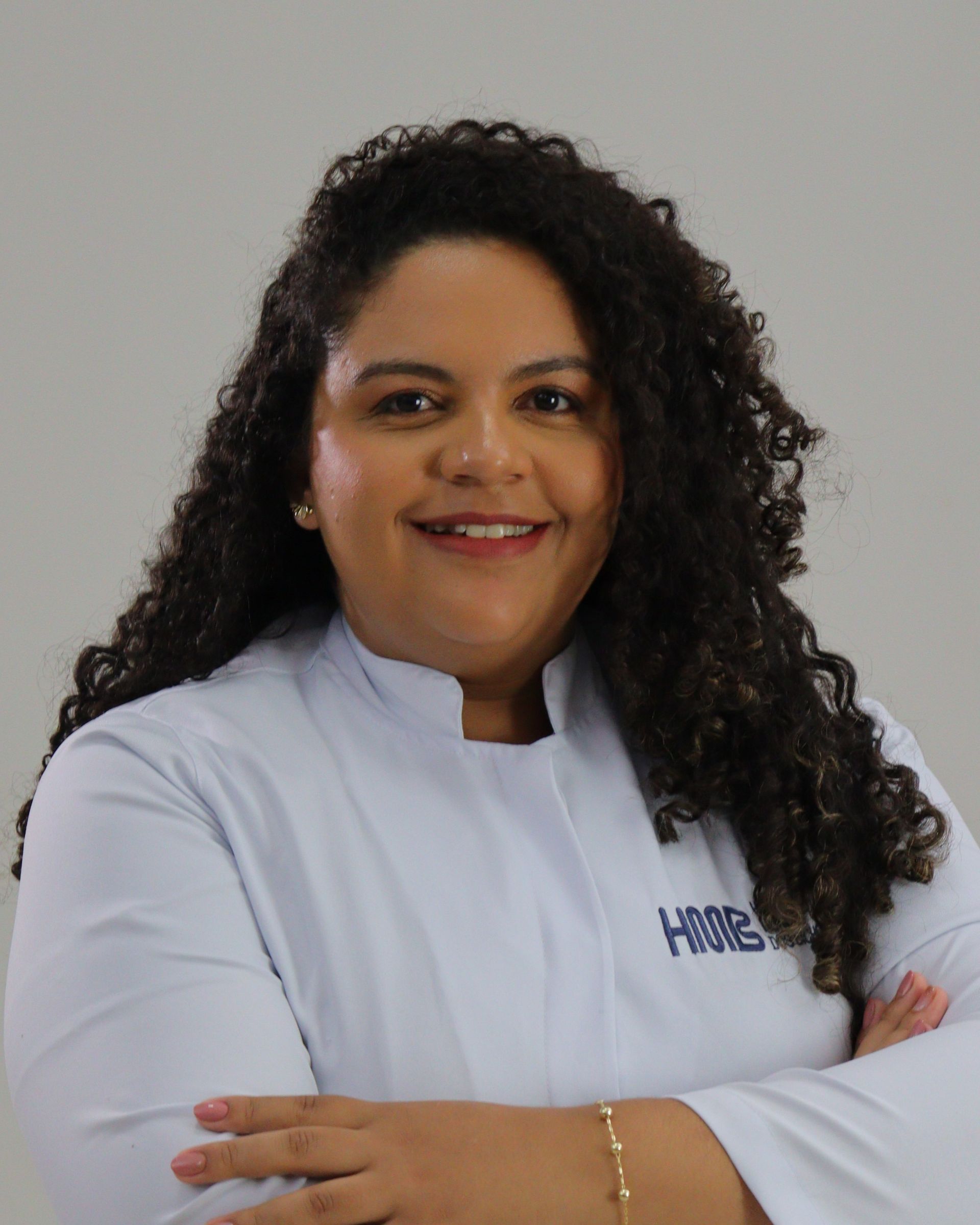 Veterinária de uniforme azul segurando um cachorrinho, sorrindo.