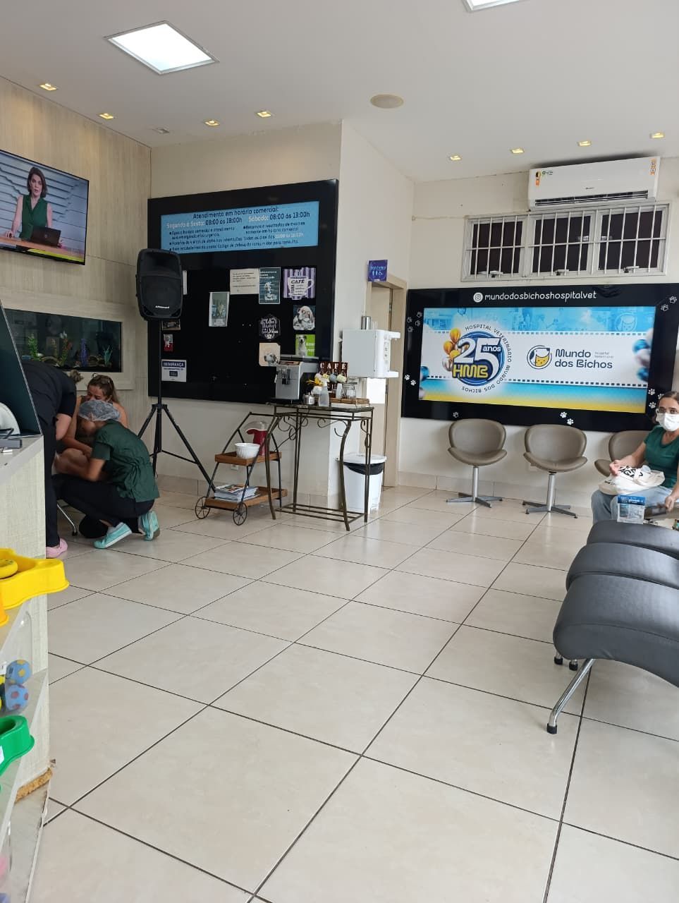 Interior de uma clínica. Pessoas de uniforme cirúrgico trabalham perto de equipamentos e expositores. 