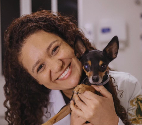 Homem de uniforme cirúrgico azul, com os braços cruzados, olhando para o lado.
