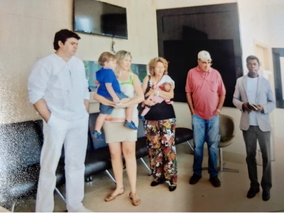 Pessoas em uma sala: um médico, uma família com crianças, um casal de idosos.