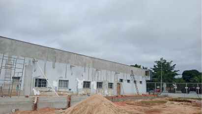 Prédio em construção com céu nublado. Vista externa com paredes inacabadas e materiais de construção.
