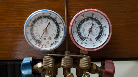HVAC gauge showing two pressure readings. Blue and red valves and brass fittings.