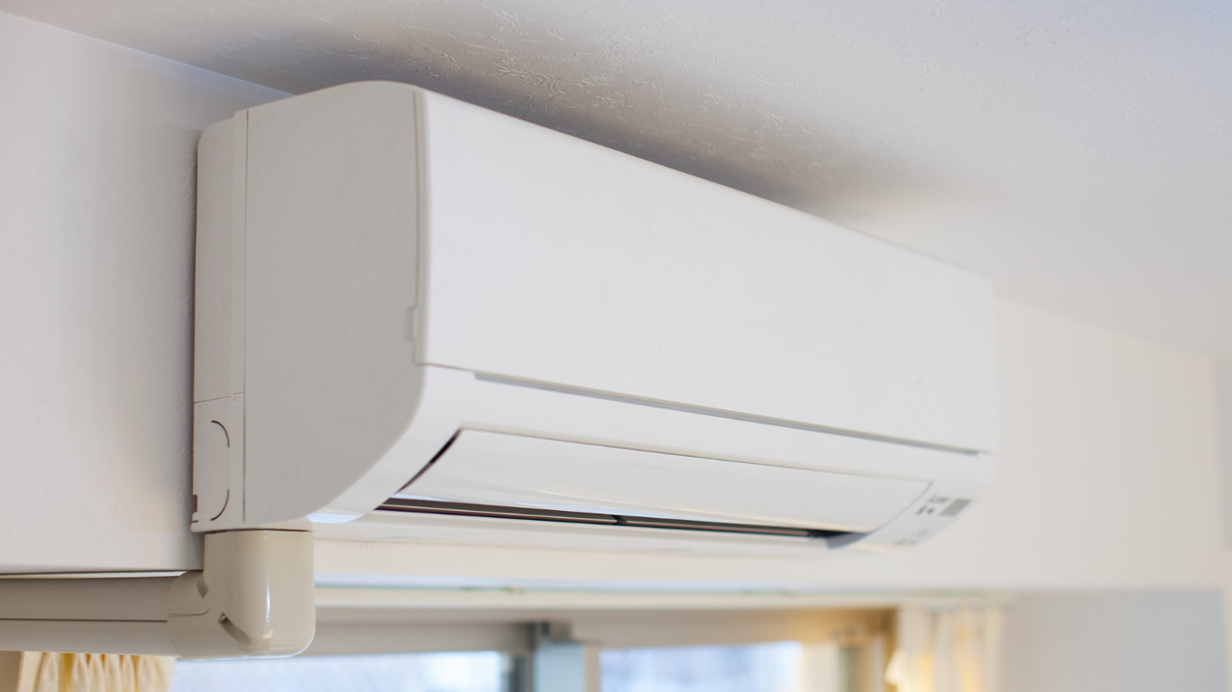 White wall-mounted air conditioner in a room, blowing cool air.