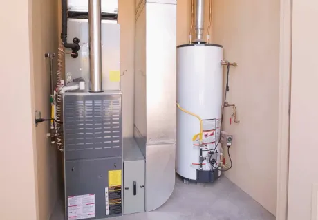 A furnace and water heater in a small, neutral-colored utility room.