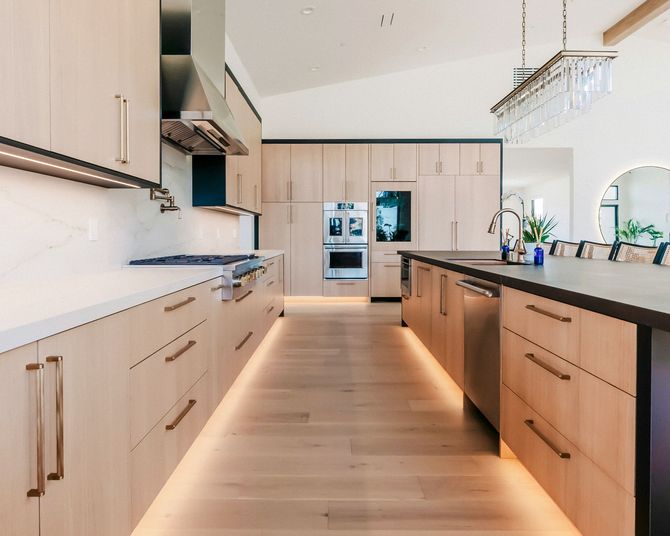 Bright modern kitchen with light wood cabinets, black countertops, and a central island under pendant lights
